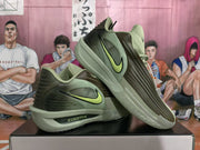 Angled view of the olive green Nike sneakers showing the contrasting Swoosh, layered side panels and translucent-looking outsole.