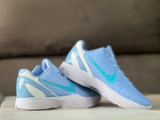 Light blue sneakers displayed in an overlapping side view with white midsoles and turquoise Swooshes.