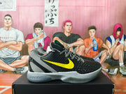 Side view of black Nike Kobe 6 basketball shoes with a yellow Swoosh and grey accents.