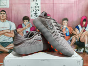Angled view of the pair highlighting the perforated upper, side branding, heel pull tabs, and orange outsole details.