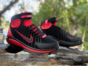 Front three-quarter view of the black and red lace-up high-top sneakers.