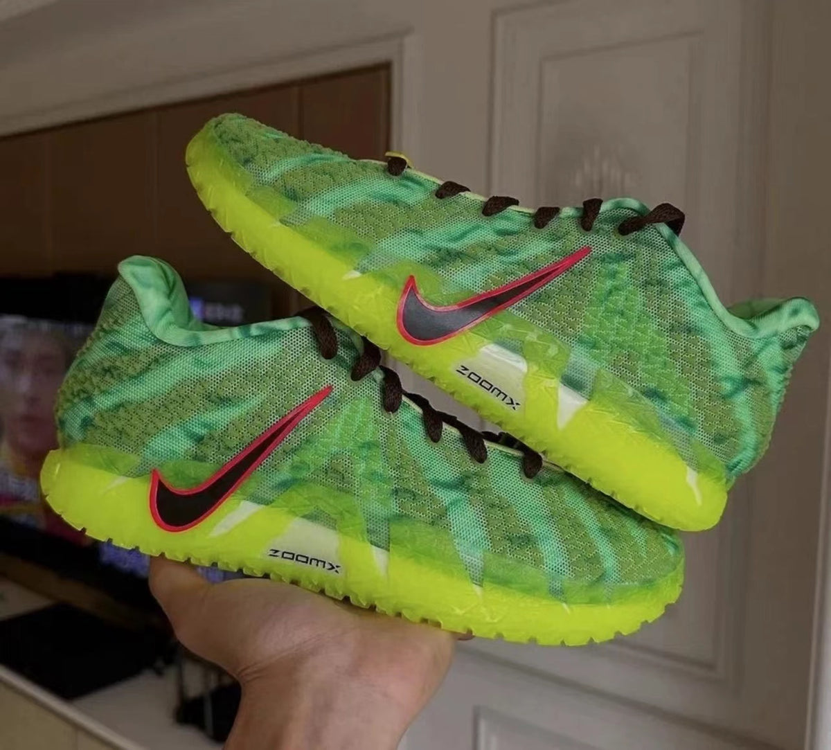 Pair of green Nike sneakers with neon yellow soles, black laces, red-edged Swoosh detailing, and visible ZoomX sidewall markings.