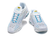 Front view of a pair of white and blue Nike Air Max Plus sneakers with lace-up closures.