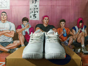 Front view of white lace-up basketball shoes with gray detailing and coral outsole accents.
