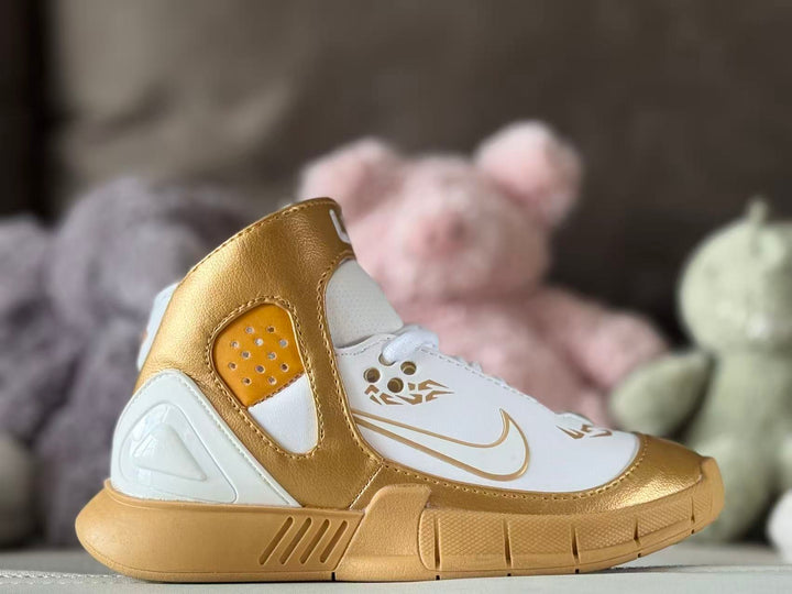 Side profile of gold and white Nike Kobe 2K5 kids' basketball shoes with a high ankle collar and patterned outsole.