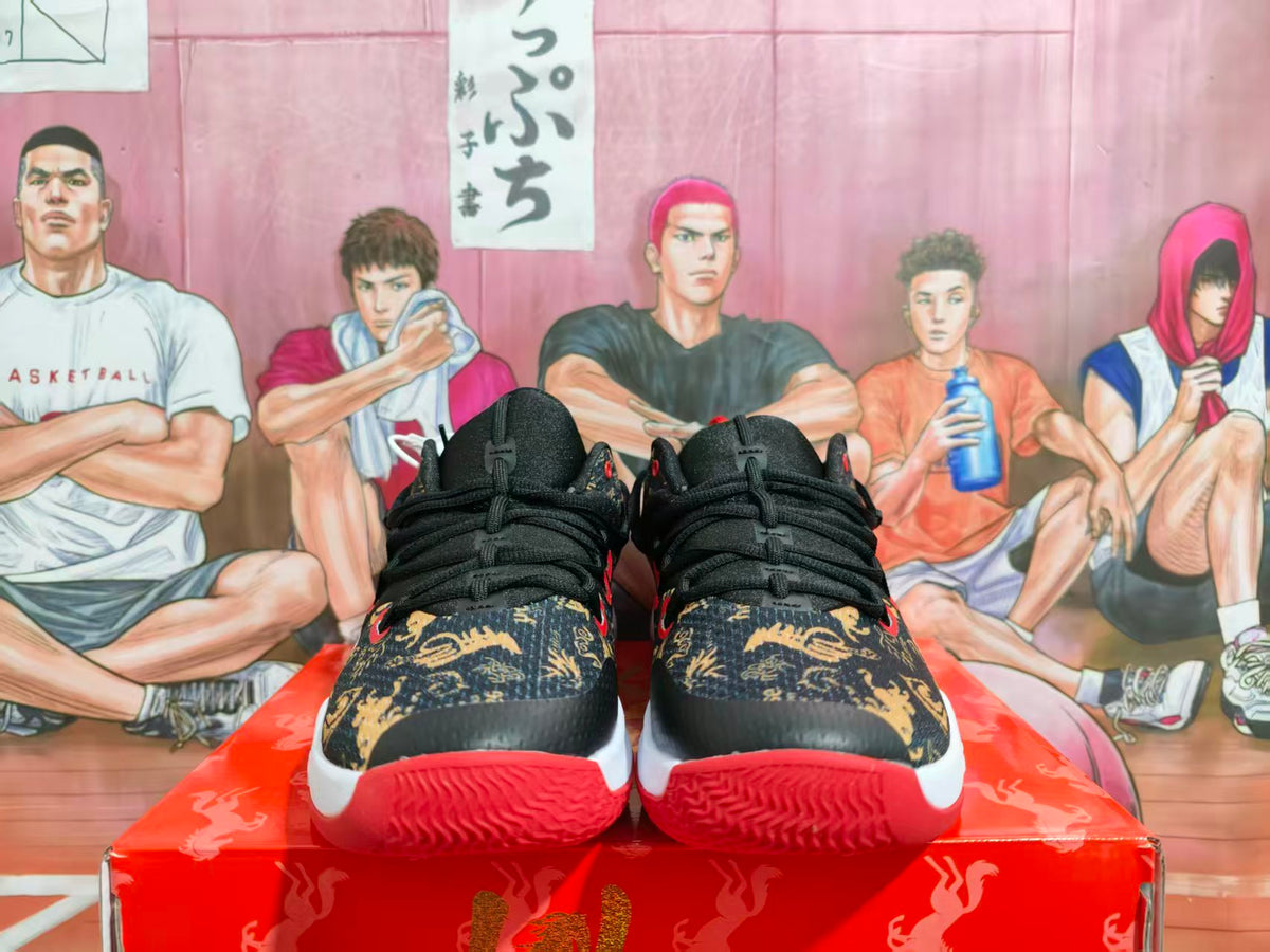 Front view of black Nike basketball sneakers with gold patterned uppers, red outsoles, and white midsoles.