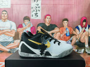 Side view of a black and white basketball sneaker with gold Swoosh branding, black laces, and a contrasting outsole.