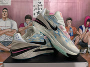 Pair of light blue camouflage-style basketball sneakers shown from a side angle, with black Swoosh logos, pink accents, and speckled midsoles.
