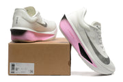 White Nike Zoom Fly 6 shoes with pale pink and black accents beside a box showing a sample size label