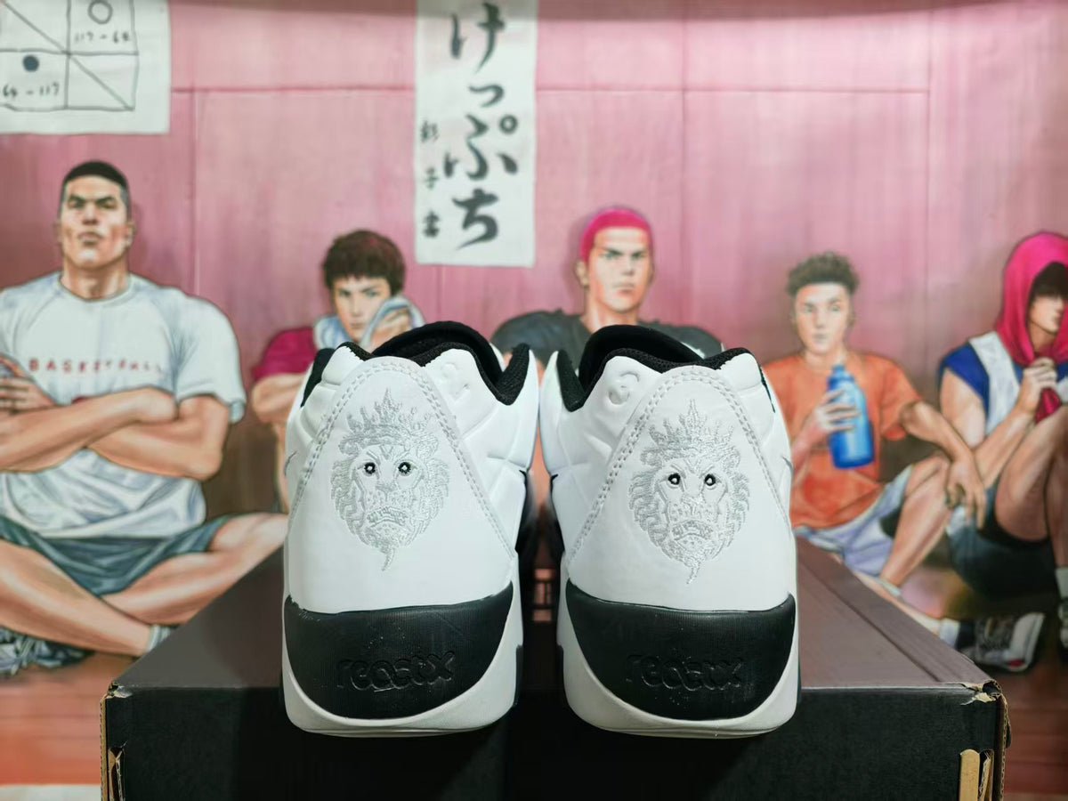 Rear view of white and black Nike basketball sneakers showing embroidered heel graphics and black heel panels.