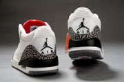Rear view of two white and black Jordan sneakers showing the Jumpman heel logos, elephant-print panels, and black heel sections.