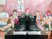 Front view of the black high-top sneakers showing the Under Armour logos on the tongues, black laces, and white textured midsoles.