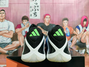 Rear view of black basketball shoes with white heel overlays and bright volt adidas tongue logos.