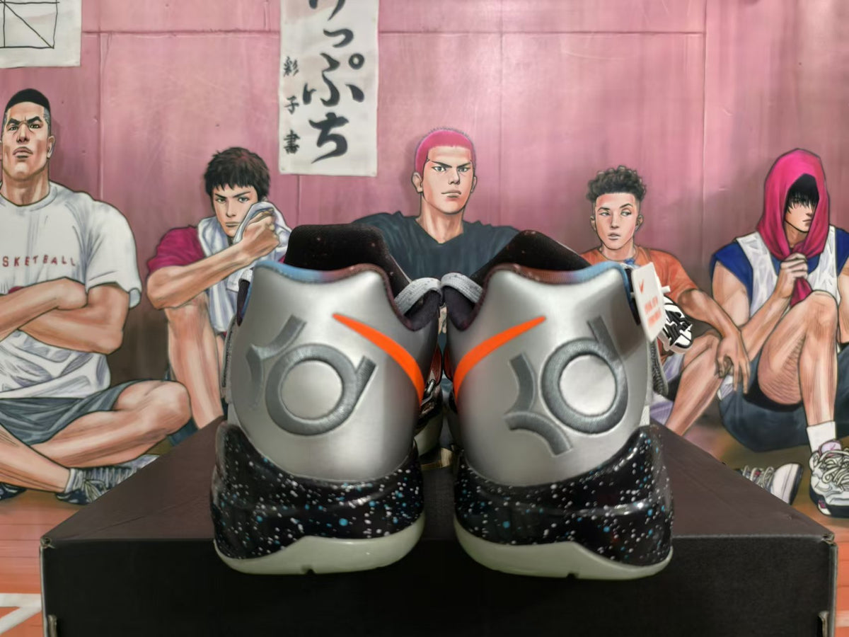 Rear view of silver and orange Nike basketball shoes with speckled black midsoles.
