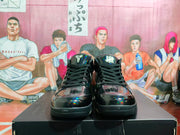 Front view of black high-top basketball sneakers with glossy panels, black laces and contrasting tongue details.