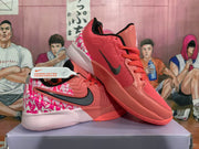 Angled view of coral pink Nike basketball sneakers showing the side branding, patterned heel and rubber outsole.
