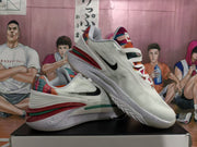 Angled view showing both white Nike basketball sneakers, patterned tongues and heels, black Swooshes, and layered midsoles.