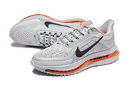 Angled view of two grey Nike Pegasus Premium shoes with black Swoosh logos and orange accents.