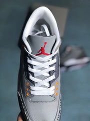 Top view of a grey sneaker tongue with a red Jumpman logo, white laces, and orange eyelets