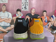 Rear view of black and yellow sneakers showing ribbed heel panels, speckled midsoles, bright green outsoles and visible “12:AM” heel labels.