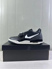 Side profile of a black and white Jordan Legacy 312 sneaker displayed on a black shoebox.
