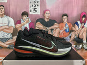 Side view of black Nike GT basketball shoes with red mesh detailing, a white Swoosh, pale green trim, and a red midsole accent.
