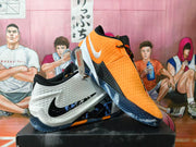 White and orange Nike basketball shoes displayed together, showing side panels and outsole details.