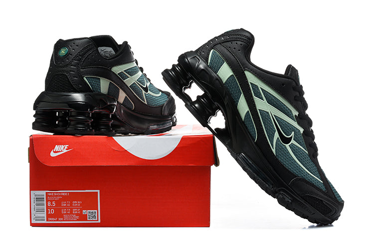 Pair of black, teal, and pale green Nike Shox Ride 2 sneakers displayed with a red shoe box.
