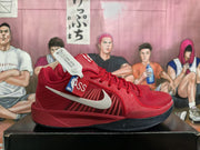 Side view showing the red upper, white Swoosh, NBA-themed hangtag, and dark contrasting outsole.