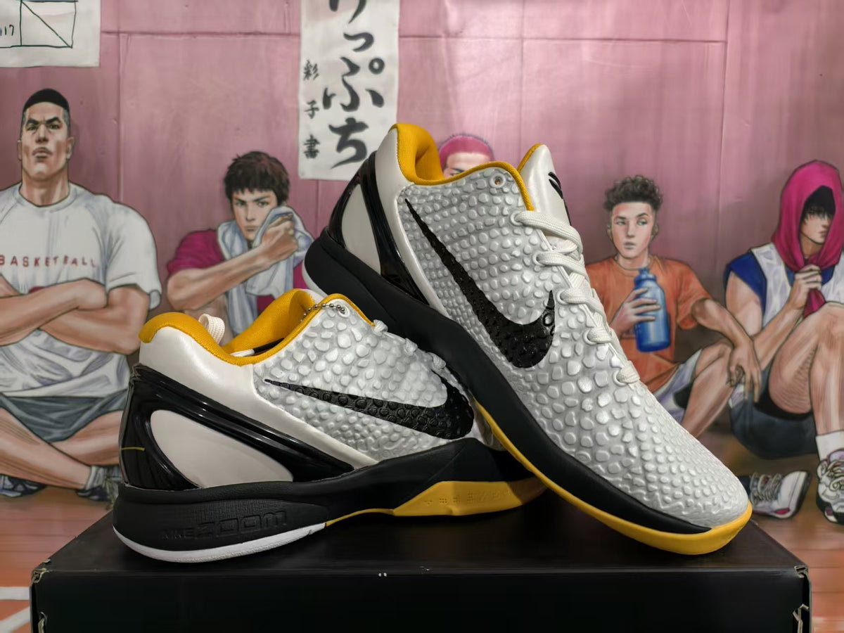 Pair of white, black, and yellow Nike basketball sneakers displayed on a box, showing the textured upper and side Swoosh.