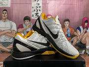 Pair of white, black, and yellow Nike basketball sneakers displayed on a box, showing the textured upper and side Swoosh.