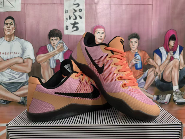 Pair of Nike basketball sneakers in a volcanic red, pink, orange, tan, and black colorway displayed on a striped shoe box.