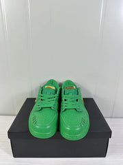 Front view of a pair of green low-top sneakers showing perforated toe boxes and matching laces.