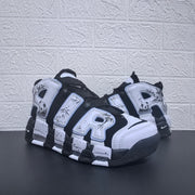 Pair of black and white Air More Uptempo sneakers showing oversized AIR lettering.