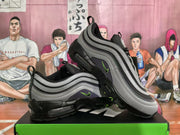 Angled view of gray and black Nike sneakers showing the side panels, green accents, heel pull tabs, and transparent sole sections.