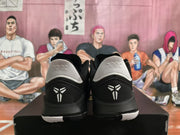 Rear view of the black sneakers showing white heel panels and Kobe logos.