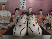 Front view of white basketball sneakers showing perforated toe boxes, white laces, and red lace accents.