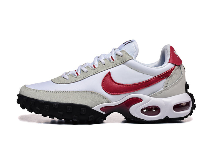 Side view of white and light gray Nike-branded sneakers with red accents and a black lugged outsole.