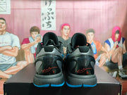Rear view of a pair of black basketball sneakers showing blue outsole accents and red signature-style heel details.