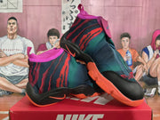 Angled view of the pair of Nike high-top basketball sneakers highlighting the camouflage-style upper, pink trim, black overlays, and orange outsole.