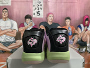 Rear view of the sneaker pair showing black heel panels, graphic heel accents, and green midsoles.