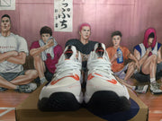 Front view of white ASICS METARISE sneakers with orange details, black toe outsoles, and white laces.