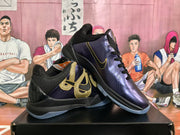 Angled view of paired dark purple and black Nike basketball sneakers displaying gold side details and black padded collars.
