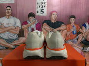 Rear view of a pair of white and red Nike sneakers on an orange box.