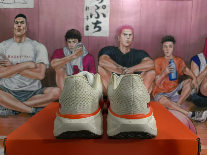 Rear view of a pair of white and red Nike sneakers on an orange box.