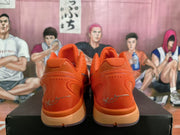 Rear view of the orange sneakers showing the sculpted heel panels, orange midsoles, and signature-style heel graphics.