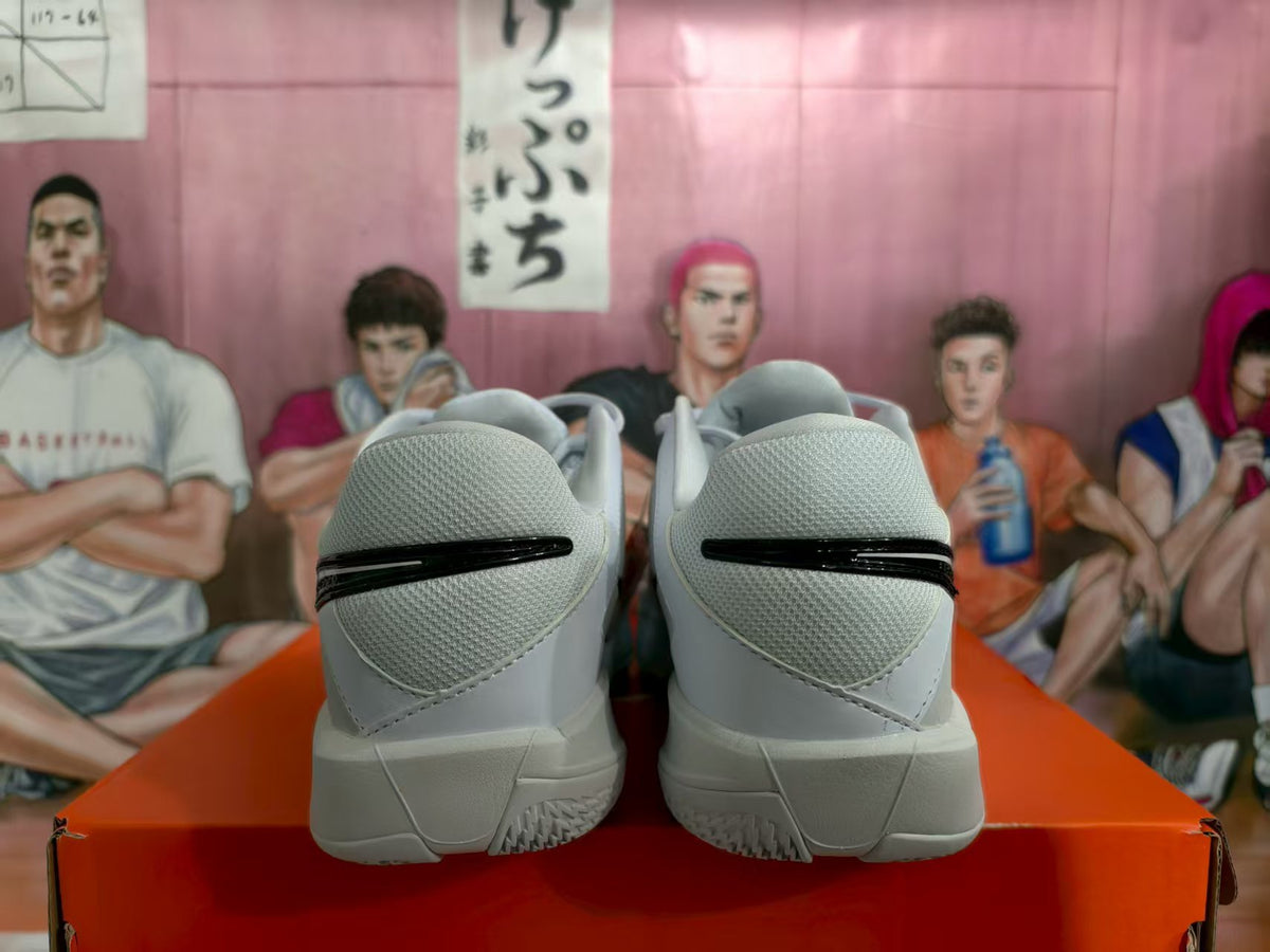 Rear view of the beige and gray Nike sneakers showing padded collars, black heel details, and textured outsoles on an orange shoebox.