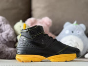 Side profile highlighting the textured black upper, ankle strap, and yellow outsole.
