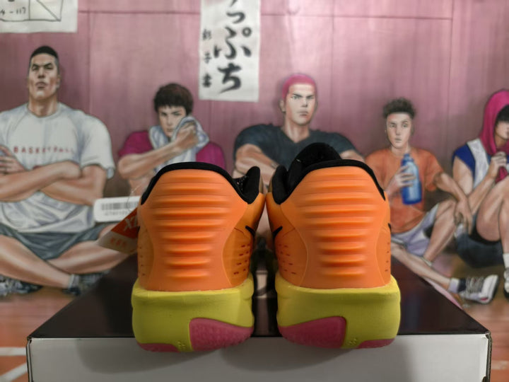 Rear view of orange and yellow Nike basketball sneakers with textured orange heel panels and green-yellow outsoles.