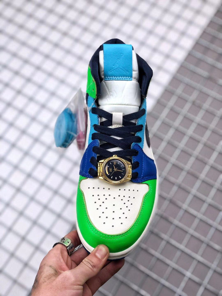Top view of a multicolor high-top sneaker with green, blue, white and navy panels, dark laces and a gold-tone watch-style lace ornament.